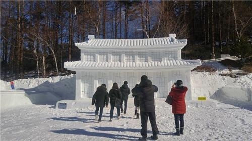 Visitors take photos in front of a snow sculpture during the Mount Taebaek Snow Festival on Jan. 16, 2017. (Yonhap)