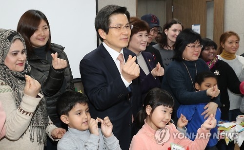 Acting President and Prime Minister Hwang Kyo-ahn and members of multicultural families pose for a photo during his visit to a state-run support center for interracial families in central Seoul on Feb. 3, 2017. (Yonhap)