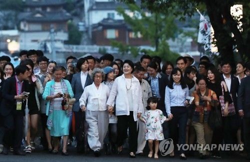 This photo, taken on June 26, 2017, shows first lady Kim Jung-sook (C) walking with citizens on a road near the presidential compound Cheong Wa Dae in Seoul. (Yonhap)