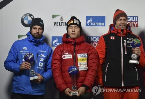 In this photo released by the Associated Press, South Korean skeleton racer Yun Sung-bin (C) poses for a photo with his trophy with second placed Martins Dukurs of Latvia (L) and third placed Dave Greszczyszyn of Canada after the men's skeleton competition at the International Bobsleigh & Skeleton Federation (IBSF) World Cup in Winterberg, Germany, on Dec. 8, 2017. (Yonhap)