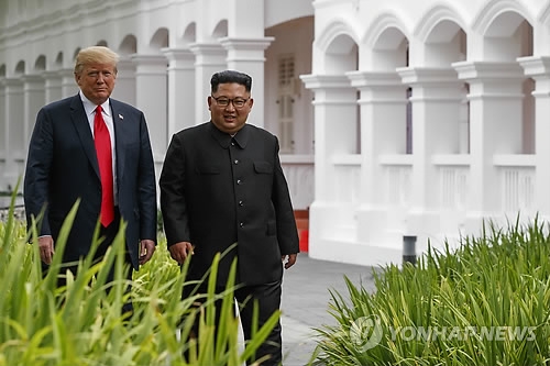 U.S. President Donald Trump (L) and North Korean leader Kim Jong-un stroll together after their luncheon meeting at the Capella Hotel in Singapore on June 12, 2018. (Yonhap)