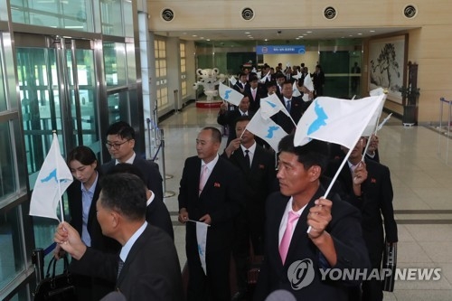 The North Korean delegation for an inter-Korean workers' football match wave unified Korean flags as they arrive in Paju, just south of the border in the South, on Aug. 10, 2018, for a three-day visit as part of the first private-level exchange between the two Koreas since the April summit of the two leaders of the states. (Yonhap) 