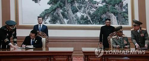 Defense Minister Song Young-moo (L) and his North Korean counterpart, No Kwang-chol, sign an agreement on reducing tensions in Pyongyang on Sept. 19, 2018, in this photo captured from a screen at the press center in Seoul. (Yonhap)