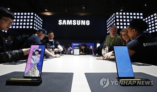In this AP photo, people try out Samsung smartphones during the 2019 Consumer Electronics Show (CES) in Las Vegas. (Yonhap)