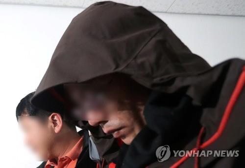 The suspect of an apartment building arson and murder case in Jinju, South Gyeongsang Province, is escorted by a police officer at the Jinju Police Station on April 17, 2019. (Yonhap)