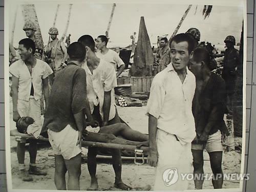 In this file photo, provided by the National Archives, Korean laborers carry an injured compatriot on a stretcher on Tarawa Island in the central Pacific Ocean. (Yonhap)