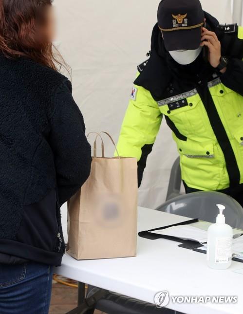 A visitor gives a paper bag containing food to a police officer at the Gwangju 21st Century Hospital in the southwestern city of Gwangju on Feb. 10, 2020. The hospital had been in quarantine since Feb. 5, when a patient infected with the new coronavirus is known to have been there. (Yonhap)