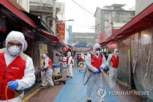 Lotte Group employees in protective suits disinfect a traditional market in Songpa Ward in southeastern Seoul on Feb. 14, 2020, in this photo provided by the retail and trading giant. Many small-scale merchants have raised concerns that COVID-19 fear is seriously hurting their businesses as fewer people leave their homes to shop. (PHOTO NOT FOR SALE) (Yonhap)