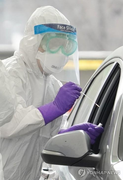 A medical worker collects a sample from a citizen in a car at a drive-through clinic in front of Seoul Olympic Main Stadium on March 3, 2020, to test for the new coronavirus. (Yonhap)