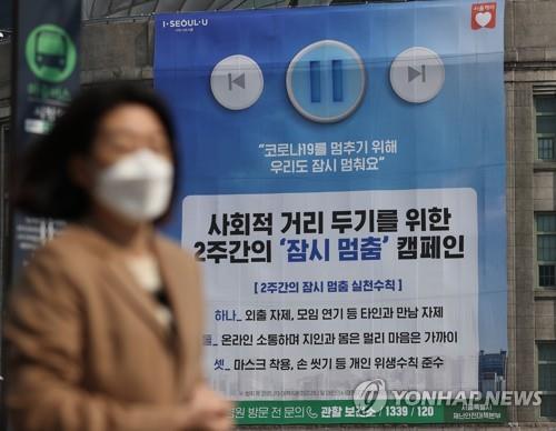 This undated file photo shows a citizen walking past a social-distancing campaign poster in Seoul. (Yonhap)	