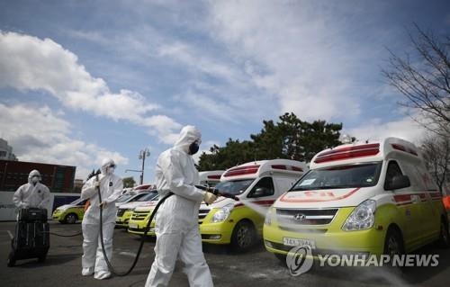 Emergency workers disinfect ambulances used for transferring the new coronavirus patients in the southeastern city of Daegu on March 29, 2020. (Yonhap) 