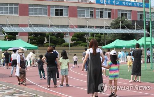 Elementary school students and their parents wait in line to take COVID-19 tests at a clinic temporarily set up at a school in the central city of Daejeon on July 2, 2020. (Yonhap)