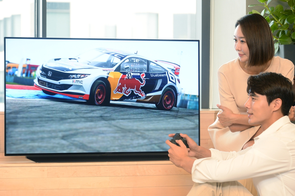 Models pose for a photo with LG Electronics Inc.'s 48-inch OLED TV, in this photo provided by the company on July 24, 2020. (PHOTO NOT FOR SALE) (Yonhap)