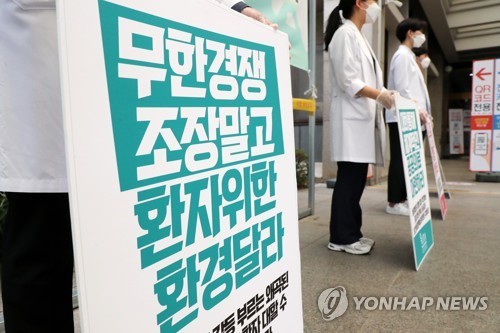 Trainee doctors holding signs denouncing the government medical reform plan take part in a strike at Ajou University Hospital in Suwon, south of Seoul, on Aug. 21, 2020. (Yonhap)