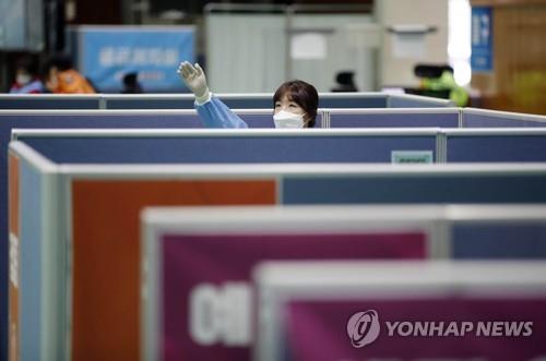 This photo provided by Gwangju's Buk District office shows a health worker clad in a protective suit calling officials at a vaccination center in Gwangju, some 330 kilometers south of Seoul, on April 27, 2021. (PHOTO NOT FOR SALE) (Yonhap)