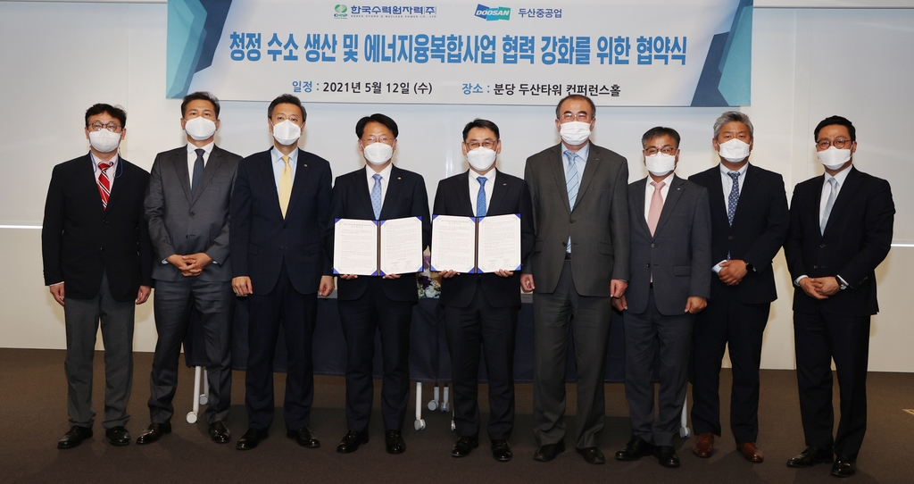 Officials from South Korean power plant builder Doosan Heavy Industries & Construction Co. and nuclear power plant operator Korea Hydro & Nuclear Power Co. (KHNP) pose for a photograph holding an agreement to cooperate on the hydrogen business on May 12, 2021, in this photo provided by the power plant builder on May 13. (PHOTO NOT FOR SALE) (Yonhap)