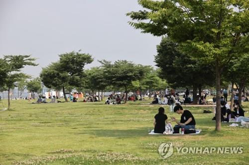 People relax at a riverside park in Seoul on June 20, 2021. (Yonhap)
