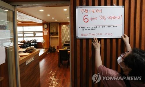 An employee puts up a sign at a restaurant in Seoul on June 28, 2021, to inform customers that gatherings of up to six people are allowed starting July 1 under the eased social distancing rules amid the coronavirus pandemic. Under the new Level 2 distancing, the ban on gatherings of five or more people will be eased to six people until July 14 in the greater Seoul area after which the ceiling will go up to eight. (Yonhap)