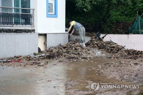 A resident removes rocks and dirt near his home in Pohang, North Gyeongsang Province, on Aug. 24. 2021. (Yonhap)