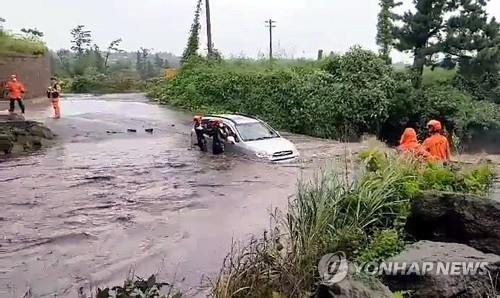 Firefighters rescue a driver trapped inside a car submerged in a flash flood on Jeju, South Korea, in this image captured from video footage provided by the Jeju Fire Station on Sept. 14, 2021. (PHOTO NOT FOR SALE) (Yonhap) 