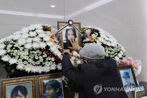 This photo, taken on Oct. 7, 2021, shows the father of a deceased Air Force noncommissioned officer touching a picture of his daughter set up at the memorial altar in a military hospital in Seongnam, south of Seoul. She took her own life in May after being sexually harassed by a colleague. (Yonhap)