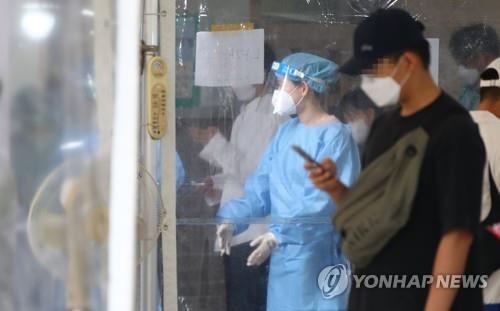 A health worker in a protective suit guides citizens at a makeshift COVID-19 testing clinic in Seoul on Oct. 10, 2021. (Yonhap)