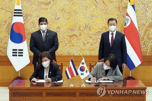 South Korean Science Minister Lim Hye-sook (R, sitting) and her Costa Rican counterpart, Paola Vega Castillo, sign a memorandum of understanding on science and technology cooperation at the presidential office in Seoul on Nov. 23, 2021, with South Korean President Moon Jae-in (R, standing) and his Costa Rican counterpart, Carlos Alvarado Quesada (L, standing), in attendance. (Yonhap)