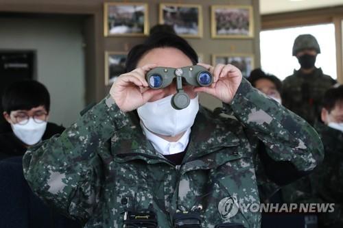 Yoon Suk-yeol, the presidential candidate of the main opposition People Power Party, looks at the North Korean side with binoculars during a visit to an observation post of the Army's 3rd Infantry Division inside the Demilitarized Zone separating the two Koreas at the central section of the inter-Korean border in Cheorwon, Gangwon Province, on Dec. 20, 2021. (Pool photo) (Yonhap)
