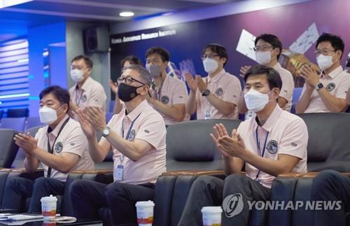 Researchers applaud at the Korea Aerospace Research Institute in Daejeon, 164 kilometers south of Seoul, on Aug. 5, 2022, as they watch a TV broadcast of a SpaceX Falcon 9 rocket carrying South Korea's first lunar orbiter, the Korea Pathfinder Lunar Orbiter, known as Danuri, lifting off from Cape Canaveral Space Force Station in Florida, the United States. (Yonhap)