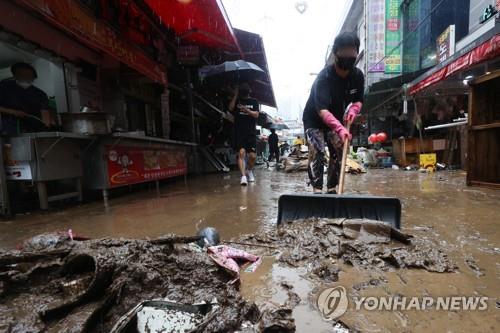 A merchant cleans up at a traditional market in Seoul's Dongjak district on Aug. 9, 2022, after record-high rainfall pounded the capital the previous day. (Yonhap)