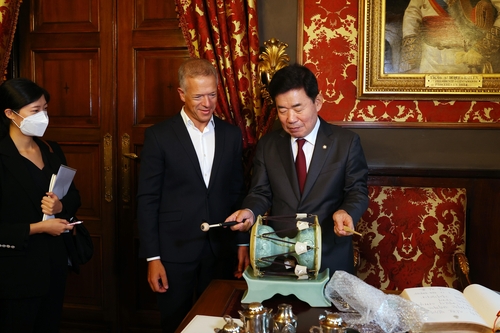 This photo, provided by National Assembly Speaker Kim Jin-pyo's office on Sept. 14, 2022, shows the parliamentary speaker (R) demonstrating a traditional Korean instrument he presented as a gift to Ander Gil Garcia, president of the Senate of Spain, during their meeting in Spain. (PHOTO NOT FOR SALE) (Yonhap)