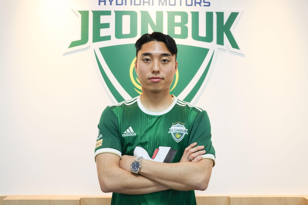 New Jeonbuk Hyundai Motors winger Lee Dong-jun poses in front of the team's logo at Jeonju World Cup Stadium in Jeonju, 200 kilometers south of Seoul, after signing with the K League 1 club on Dec. 22, 2022. Photo courtesy of Jeonbuk. (PHOTO NOT FOR SALE) (Yonhap)