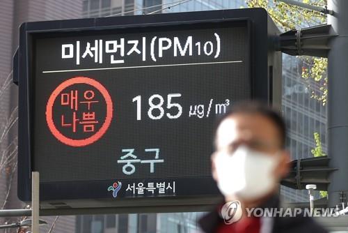 A pedestrian walks in front of an electronic display showing the fine dust level for the air in Seoul on April, 12. 2023. (Yonhap)