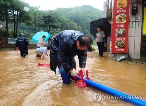This photo provided by a reader shows residents and government workers draining roads in the southern city of Gunsan on July 14, 2023. (PHOTO NOT FOR SALE) (Yonhap)