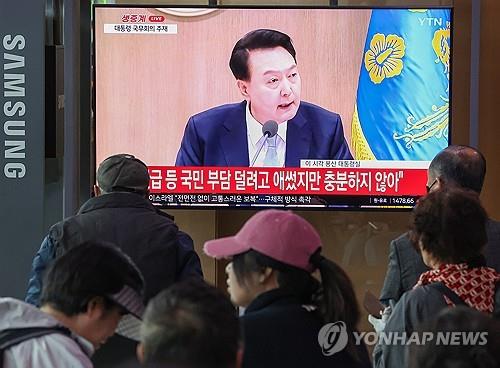 People watch a live TV broadcast of President Yoon Suk Yeol's remarks during a Cabinet meeting at Seoul Station in the capital on April 16, 2024. (Yonhap)