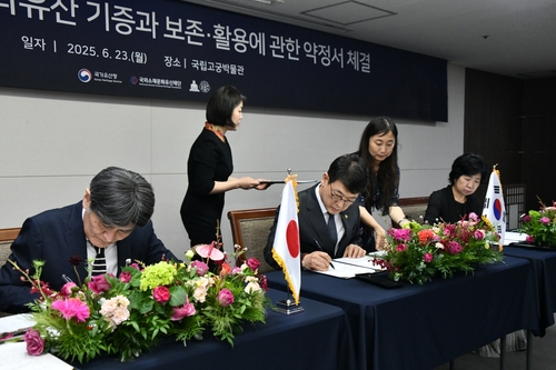 Takao Sato, chief priest of Kotoku-in, a Buddhist temple in Kamakura, Japan; Choi Eung-chon, head of the Korea Heritage Service (KHS); and Kim Jung-hee, head of the Overseas Korean Cultural Heritage Foundation, (from L to R) sign an agreement on the donation of Gwanwoldang, a building believed to be a royal shrine from the Joseon Dynasty (1392-1910), at the National Palace Museum of Korea in Seoul on June 23, 2025, in this photo provided by the KHS. (PHOTO NOT FOR SALE) (Yonhap)
