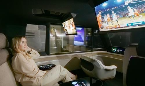 Sur cette photo fournie par LG Display, le jeudi 5 janvier 2023, une femme regarde un programme sportif sur un écran enroulable dans un concept-car autonome de l'entreprise. (Revente et archivage interdits) 