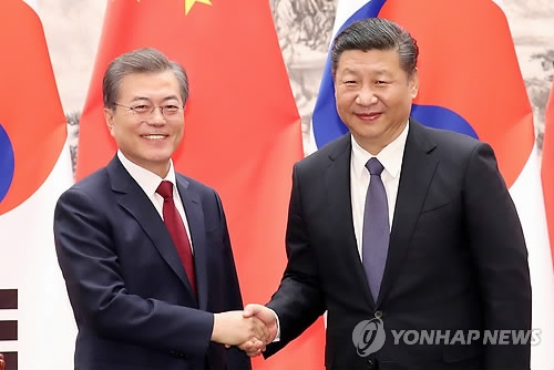 会談で握手を交わす文大統領（左）と習主席＝１４日、北京（聯合ニュース）