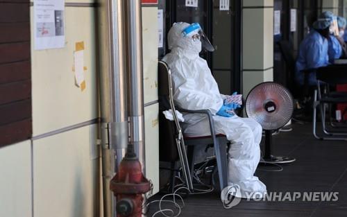 ソウルの松坡区保健所に設置されている新型コロナウイルス検査所で、スタッフが使い捨てカイロで寒さをしのいでいる＝３０日、ソウル（聯合ニュース）