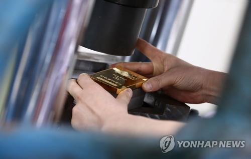 서울 종로구 한국금거래소 본사에서 직원이 기계에서 찍어낸 골드바를 꺼내고 있다. [연합뉴스 자료사진]