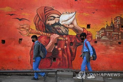 인도 뉴델리의 코로나19 방역 벽화 앞을 지나는 학생. 