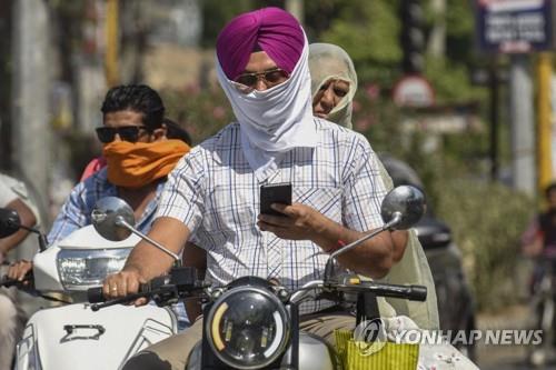 폭염 속에 얼굴 가리고 오토바이 탄 인도인