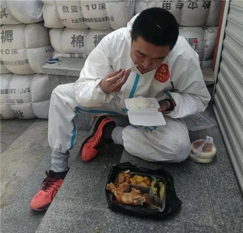 바닥에 앉아서 식사하는 단둥 자원봉사자 