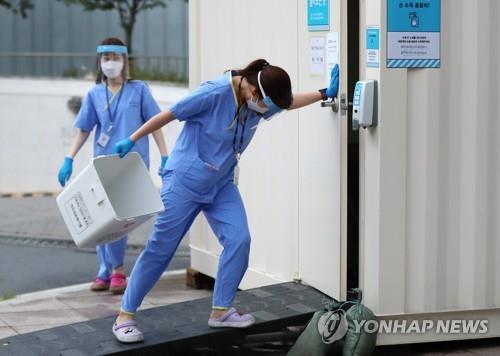 Las trabajadoras sanitarias se preparan para trabajar, el 27 de agosto de 2020, en una clínica provisional de detección del COVID-19, al aire libre, en Seúl.
