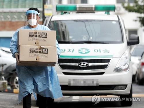 La foto, tomada el 19 de octubre de 2021, muestra a un trabajador médico transportando kits de autoprueba del COVID-19 para los pacientes de coronavirus asintomáticos o con síntomas leves que se encuentran en casa atendiéndose a sí mismos, en Incheon, al oeste de Seúl.
