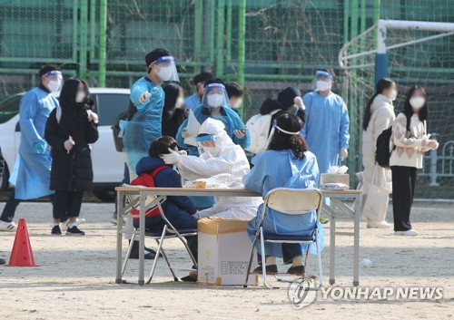 Los trabajadores sanitarios, vestidos con equipos de protección sanitaria, realizan pruebas de COVID-19, el 7 de diciembre de 2021, a los estudiantes de una escuela primaria, en la ciudad sudoccidental de Gwangju.