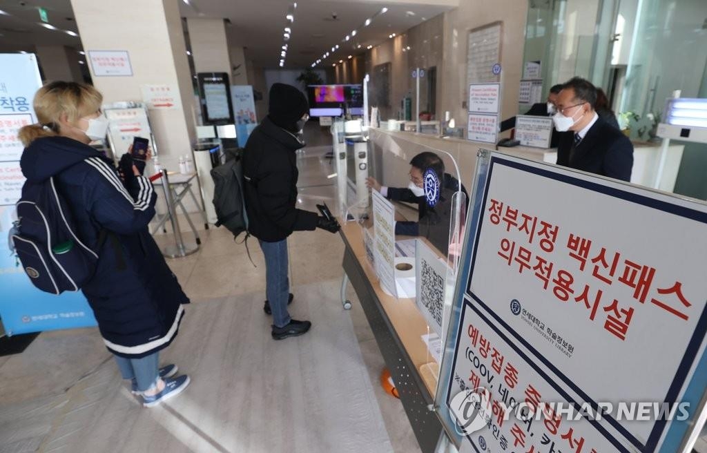 La foto de archivo, tomada el 13 de diciembre de 2021, muestra a unos estudiantes mostrando sus certificados de vacunación antes de ingresar en la biblioteca de la Universidad Yonsei, en Seúl.