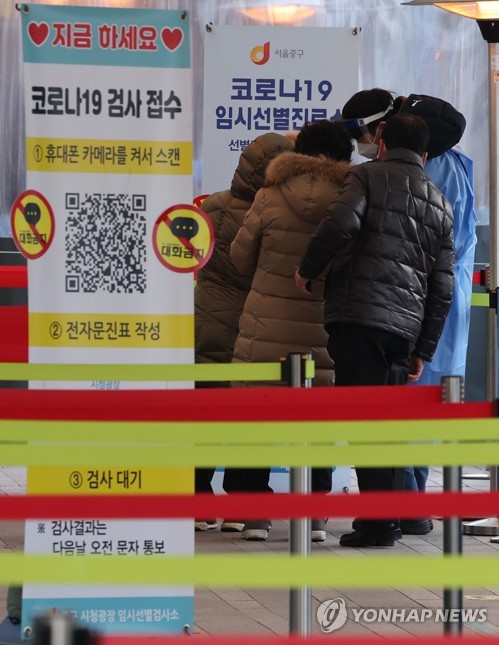 Un trabajador médico orienta a las personas que esperan en fila para someterse a las pruebas del nuevo coronavirus, el 5 de enero de 2022, en una clínica provisional, frente al Ayuntamiento de Seúl, en la capital surcoreana.