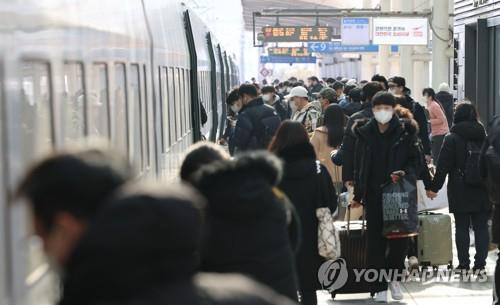 Los viajeros se suben a bordo de un tren en la Estación de Seúl, en la capital surcoreana, el 28 de enero de 2022, antes de la festividad extendida del Año Nuevo Lunar.