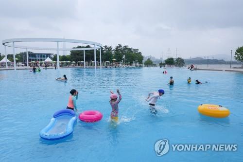Las personas disfrutan de las piscinas en el parque del río Hangang, en Seúl, el 24 de junio de 2022, el día en que cuatro piscinas al aire libre y dos piscinas para niños en la ribera del río Hangang abrieron, el mismo día, tras una suspensión de dos años a causa de la pandemia del COVID-19.
